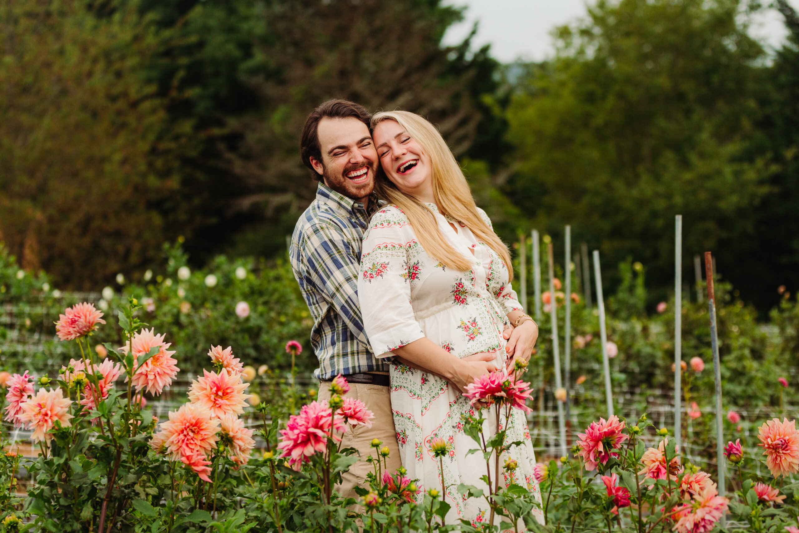 laughing couple in a maternity photo session in a field of flowers