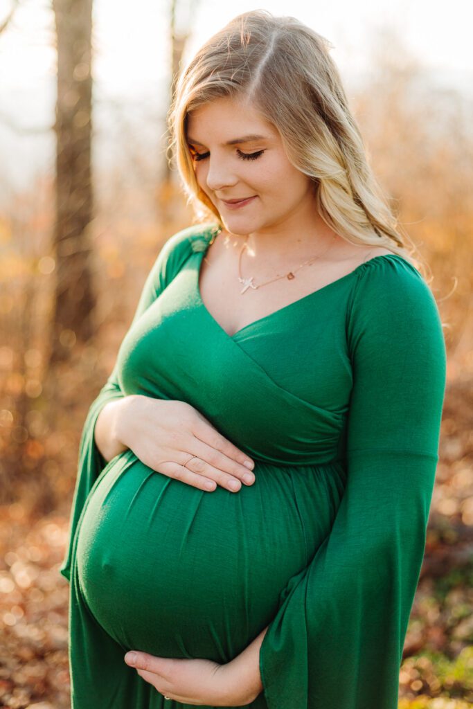 Expecting mother at 36 weeks, standing on a scenic overlook with a full belly, wearing a fitted gown and embracing her pregnancy journey