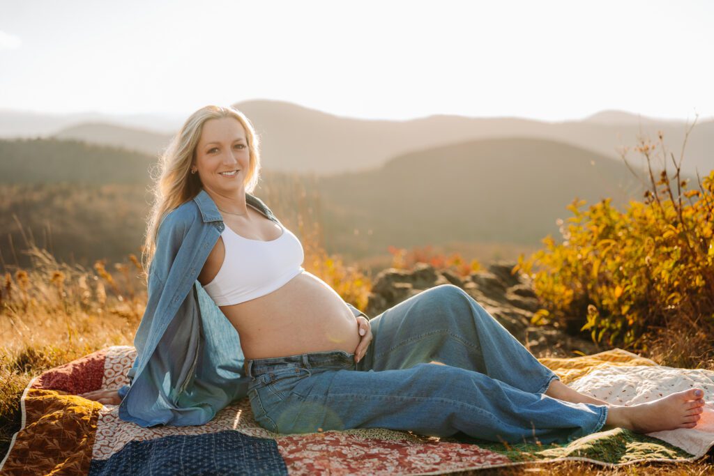 Comfortable pregnant woman relaxing on a mountaintop at sunset