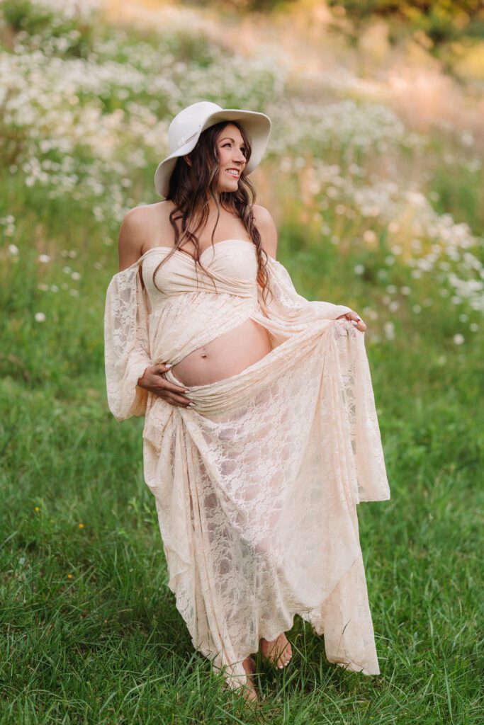 pregnant woman wearing a hat in a daisy field during Asheville maternity session