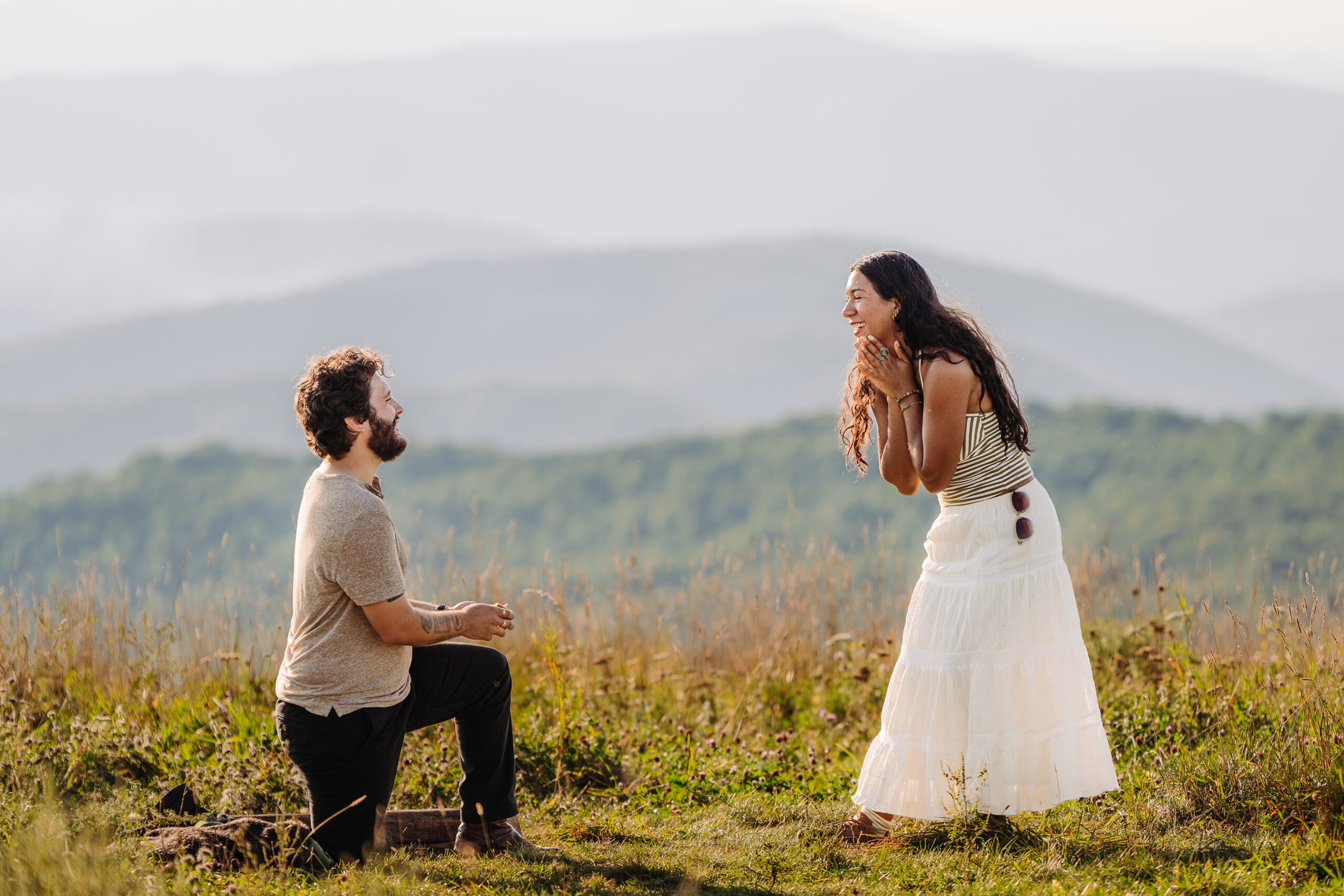 Andy kneels with the ring as Richelly smiles with her hands beneath her chin during their Max Patch proposal.